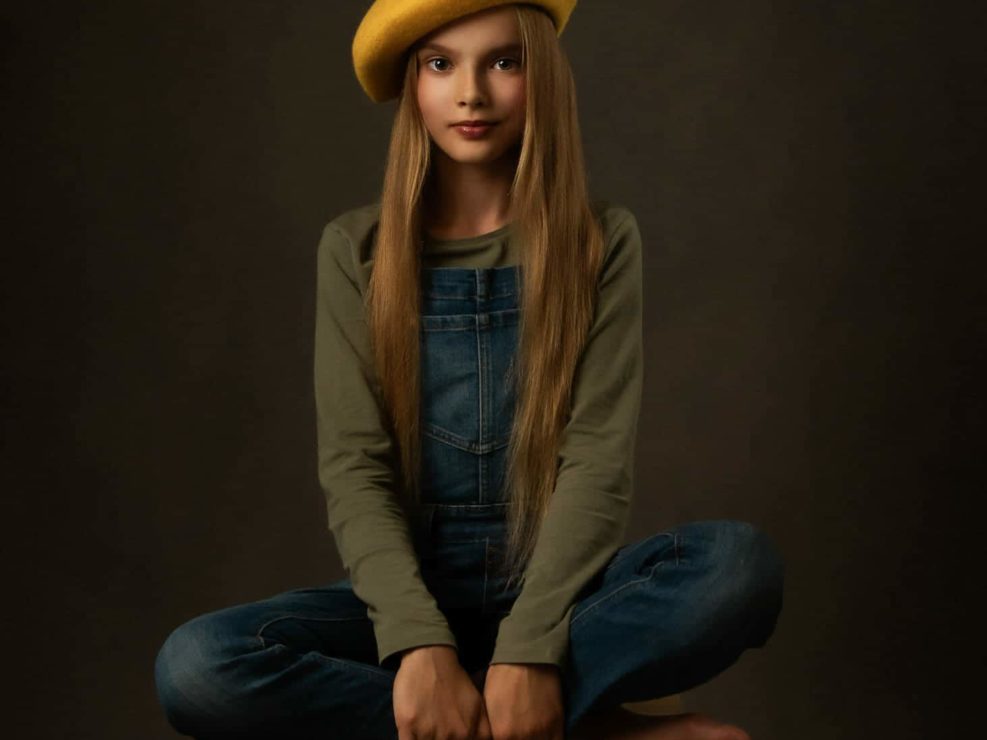 Nuori tyttö keltaisessa hatussa ristissä istumassa