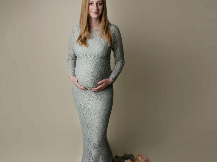 Pregnant woman in green dress surrounded by flowers
