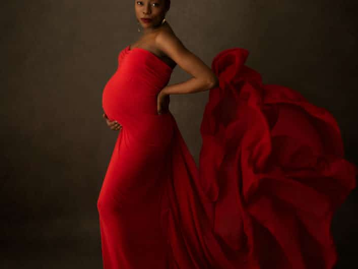 Tummaihoinen raskaana oleva nainen punaisessa raskausmekossa