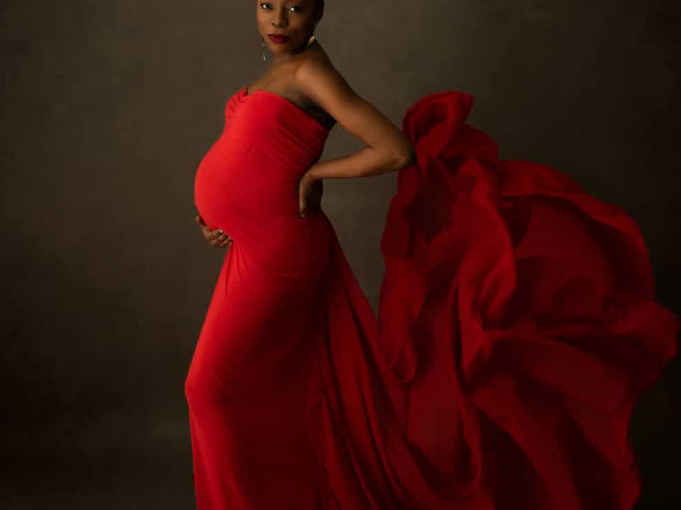 Dark skin pregnant woman posing in a red dress