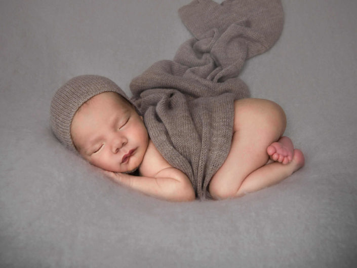 Vastasyntynyt nukkuva vauva ruskeaan huivin kanssa vauvakuvauksessa