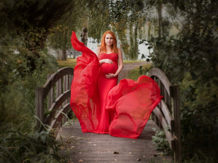 raskaana oleva nainen punaisessa mekossa puistossa