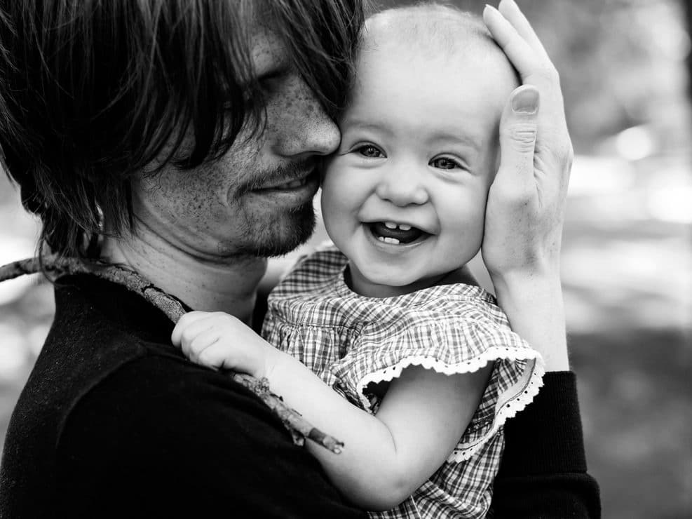 Isä halaamassa hymyilevä pikku tytärtä